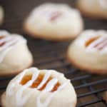 Apricot thumbprint cookies drizzled with icing and placed on a cooling rack.