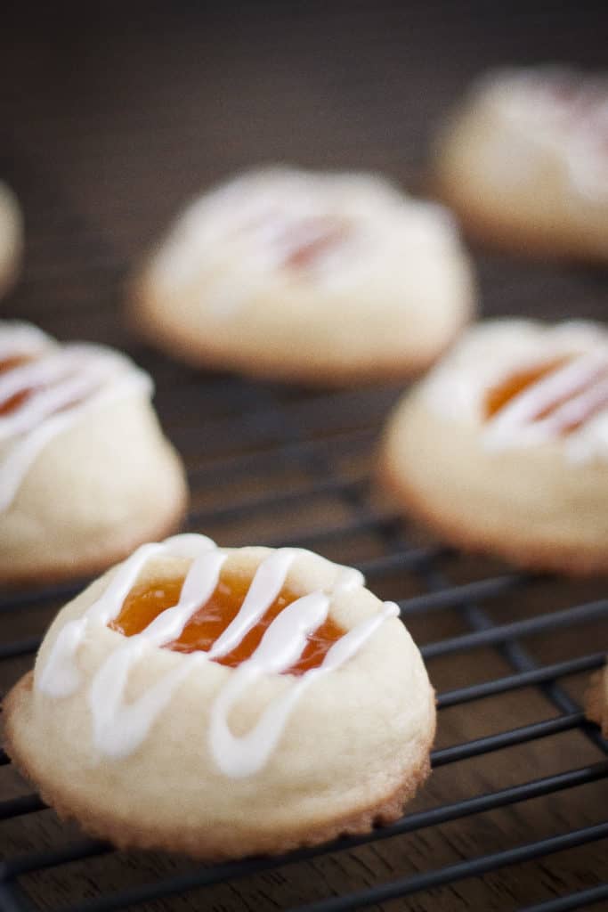Apricot thumbprint cookies drizzled with icing and placed on a cooling rack.
