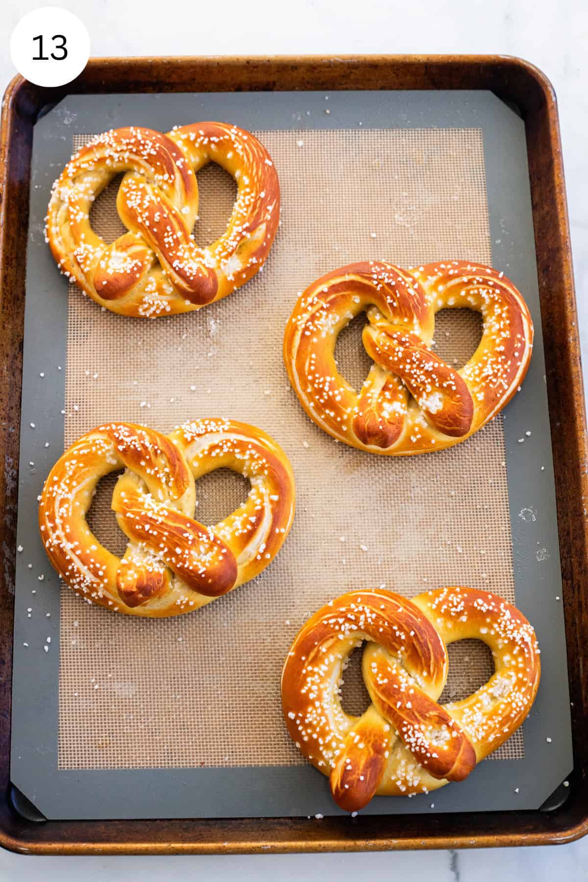 Baked pretzels on a baking sheet lined with silicone baking mat.