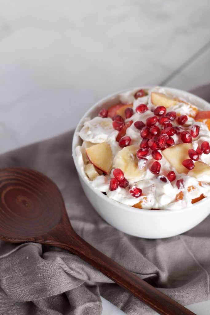 A refreshing winter pomegranate fruit salad, perfect for the holidays! Packed with pomegranate seeds, apples, mandarin oranges, bananas and whipped cream.