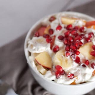 A refreshing winter pomegranate fruit salad, perfect for the holidays! Packed with pomegranate seeds, apples, mandarin oranges, bananas and whipped cream.