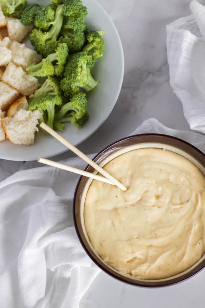 A bowl of cheese fondue on a white surface.