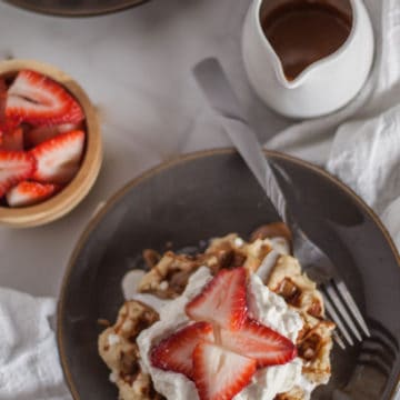 Belgian liege waffles topped with strawberries, whipped cream and cookie butter.