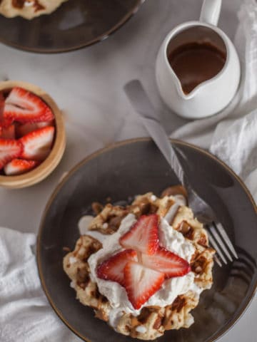 Belgian liege waffles topped with strawberries, whipped cream and cookie butter.