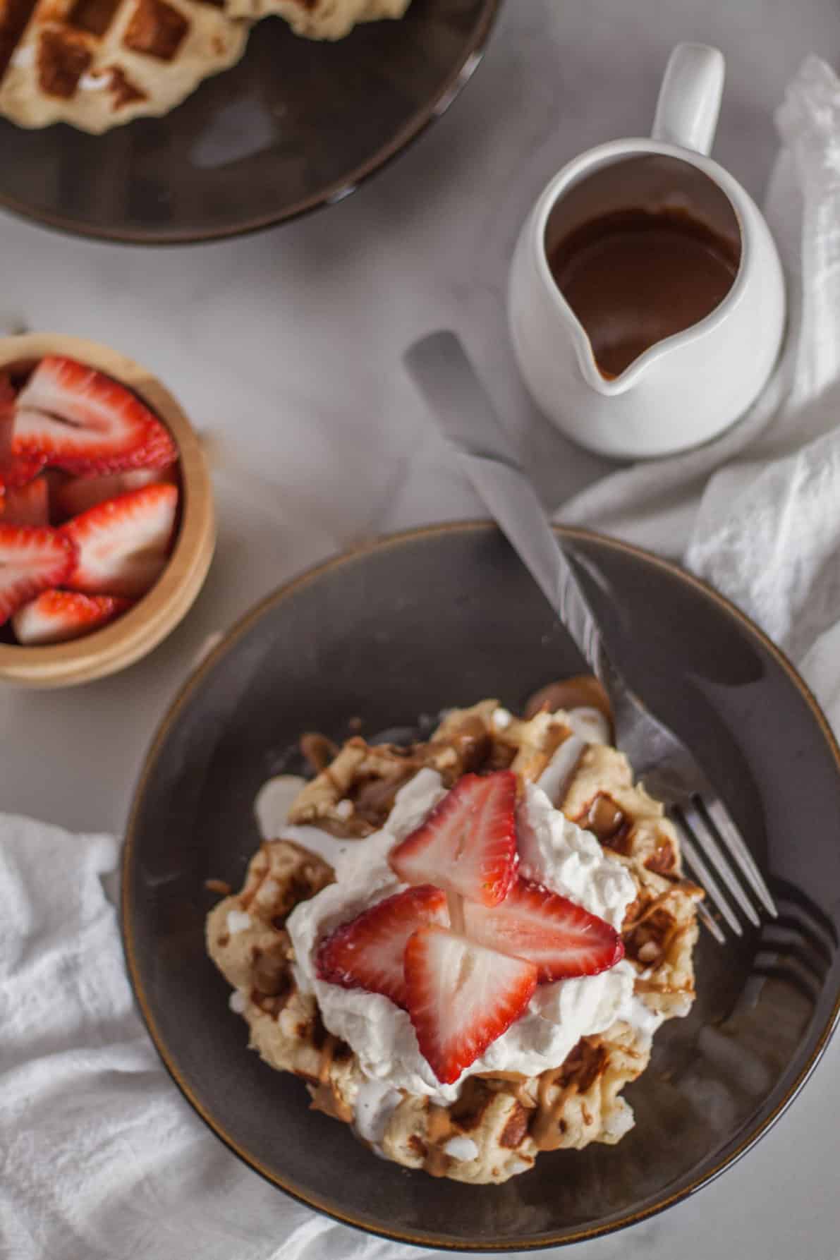 Belgian liege waffles topped with strawberries, whipped cream and cookie butter.