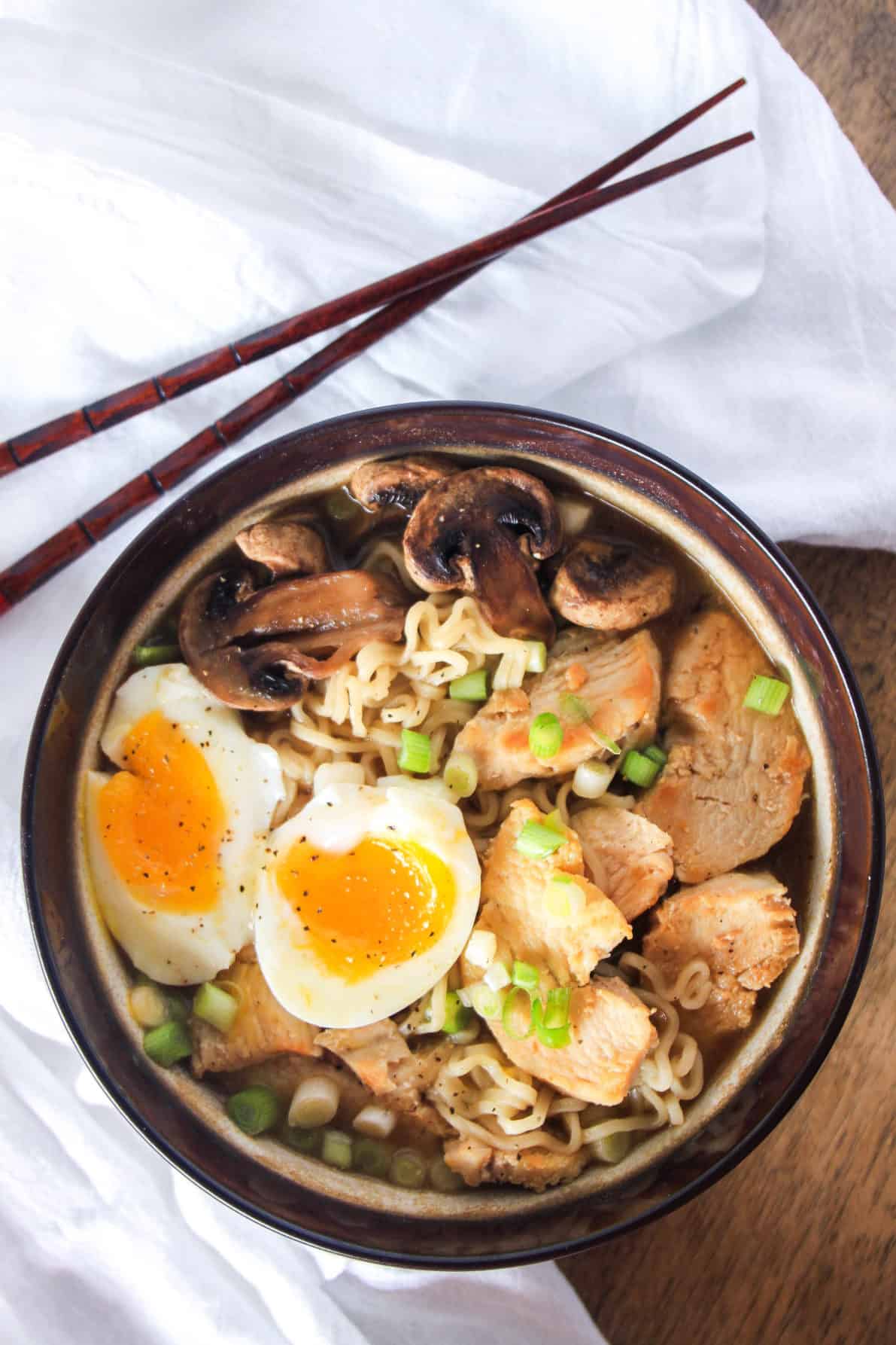 A bowl of chicken ramen with chopsticks on a white towel.