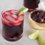 Hibiscus iced tea in a glass garnished with a lime wedge.
