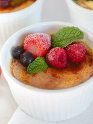 Creme brulee in a white ramekin on a marble surface.