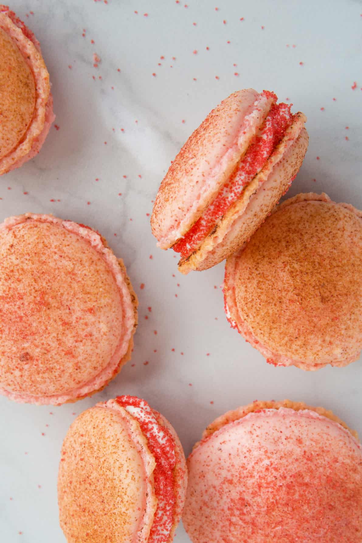 Strawberry cheesecake macarons on a marble surface.