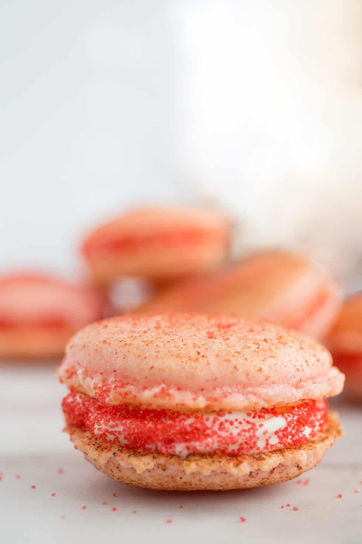 Strawberry cheesecake macarons on a marble surface.