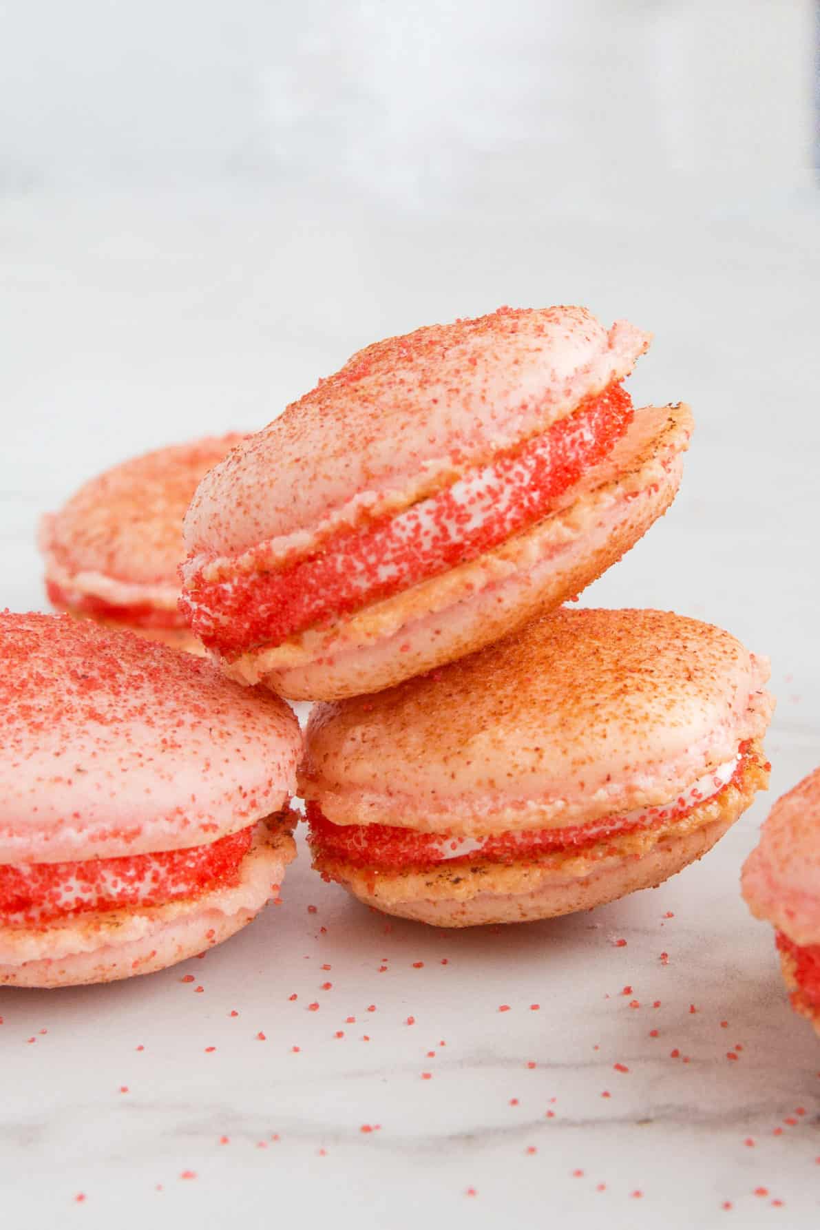 Strawberry cheesecake macarons stacked on a marble surface.