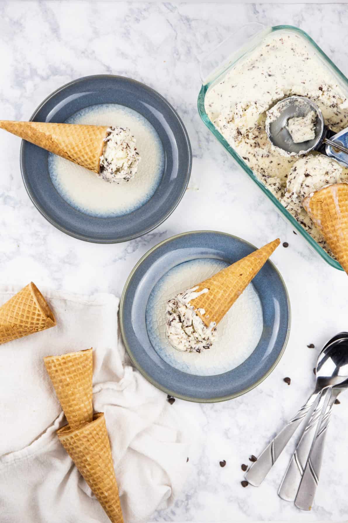 Waffle cones with Stracciatella Gelato laying on plates.