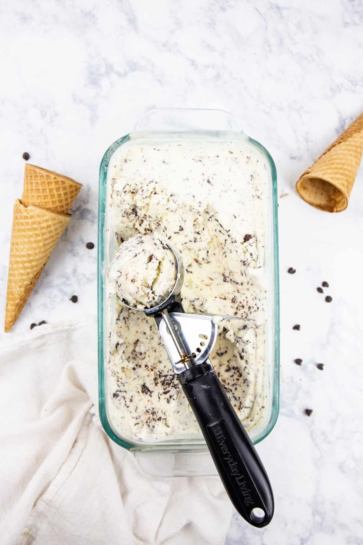 Stracciatella Gelato in a glass pan with an ice cream scoop.