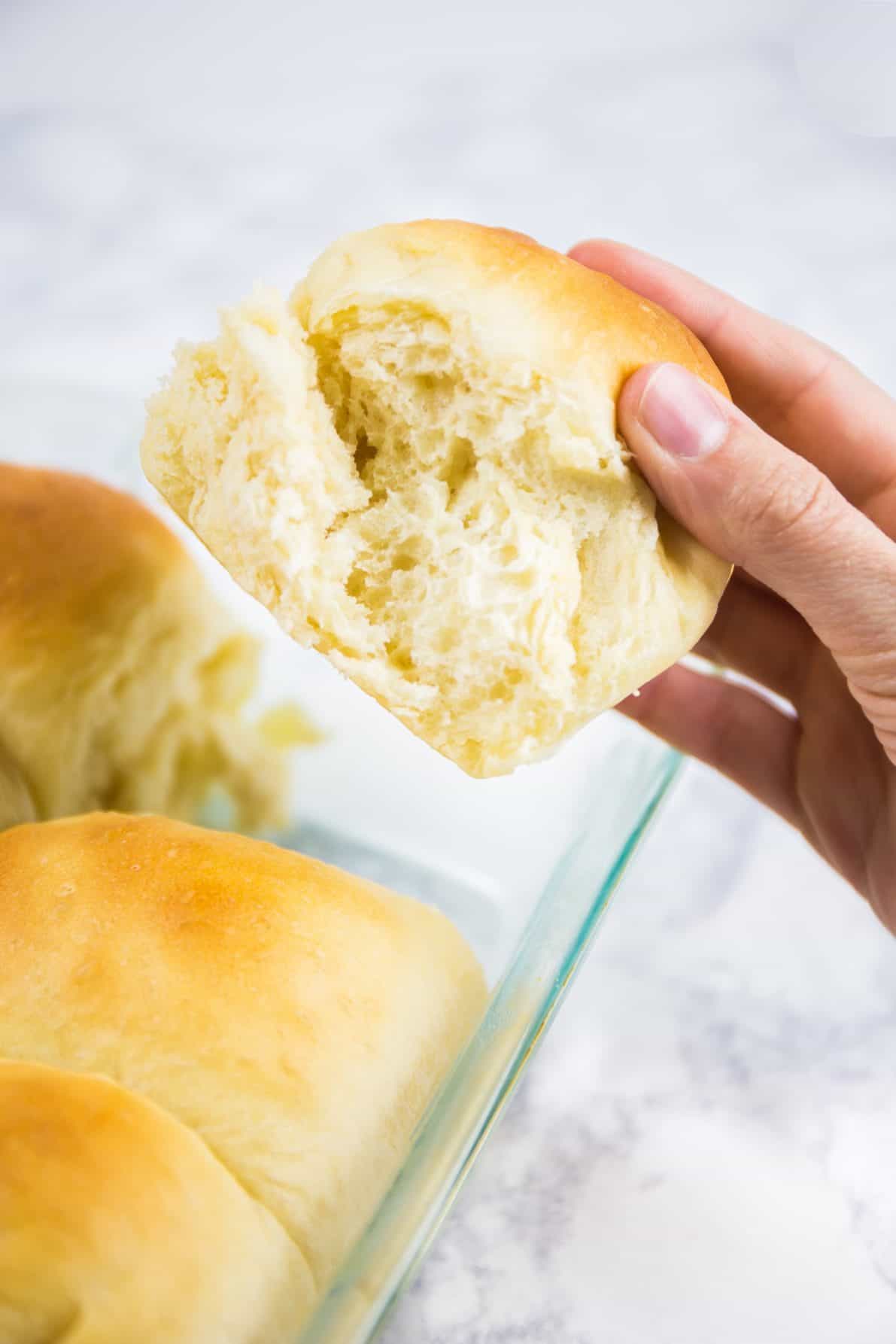 Someone's hand grabbing a milk bread roll out of the pan.