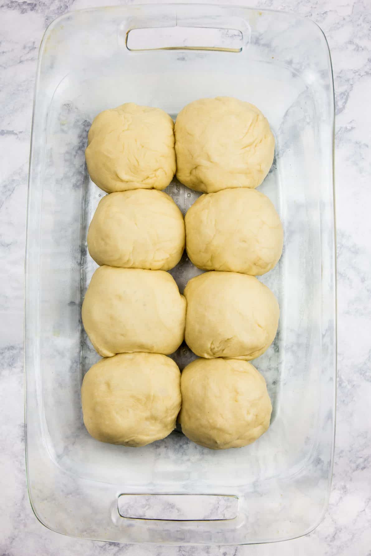 Milk bread rolls in a glass pan prior to baking.