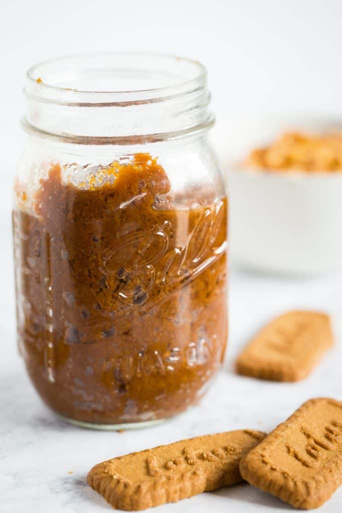 A jar of cookie butter next to speculoos cookies.