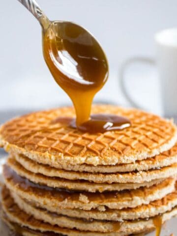 Stroopwafels in a stack with a spoon drizzling caramel on top.