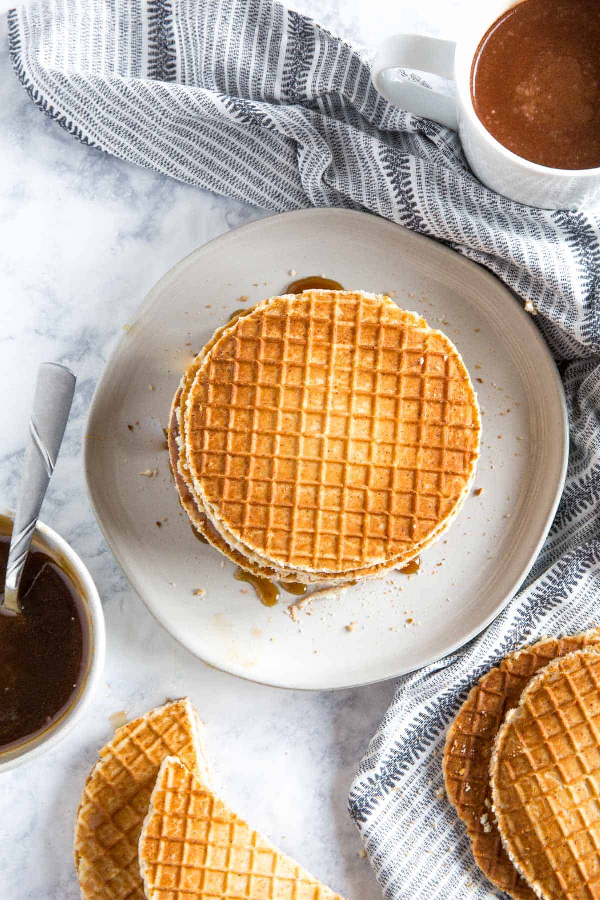 Stroopwafels on a white plate on a marble surface.