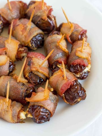 A plate full of bacon wrapped dates with cream cheese.