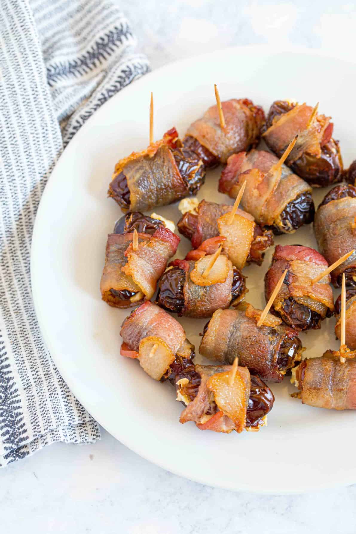 A plate of bacon wrapped dates with cream cheese.