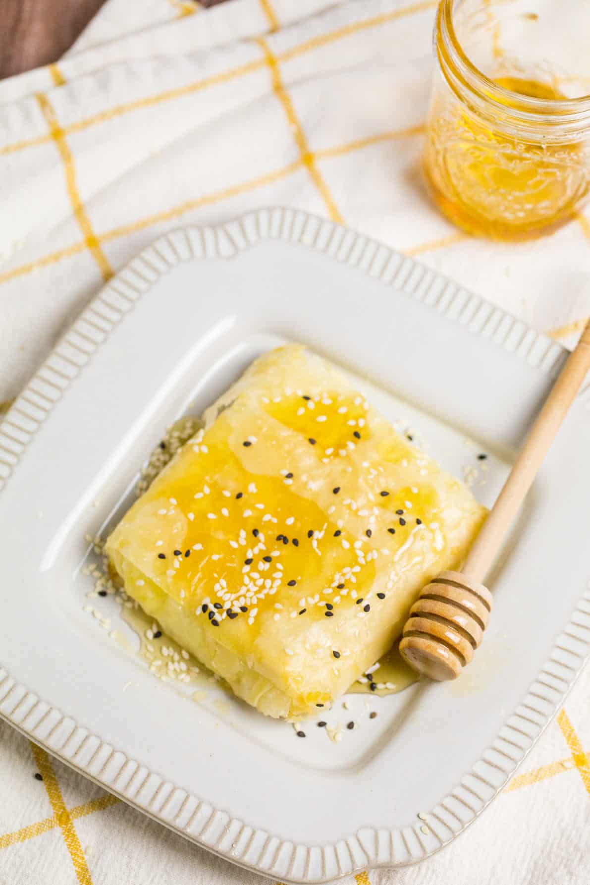 Baked feta with honey on a white plate.
