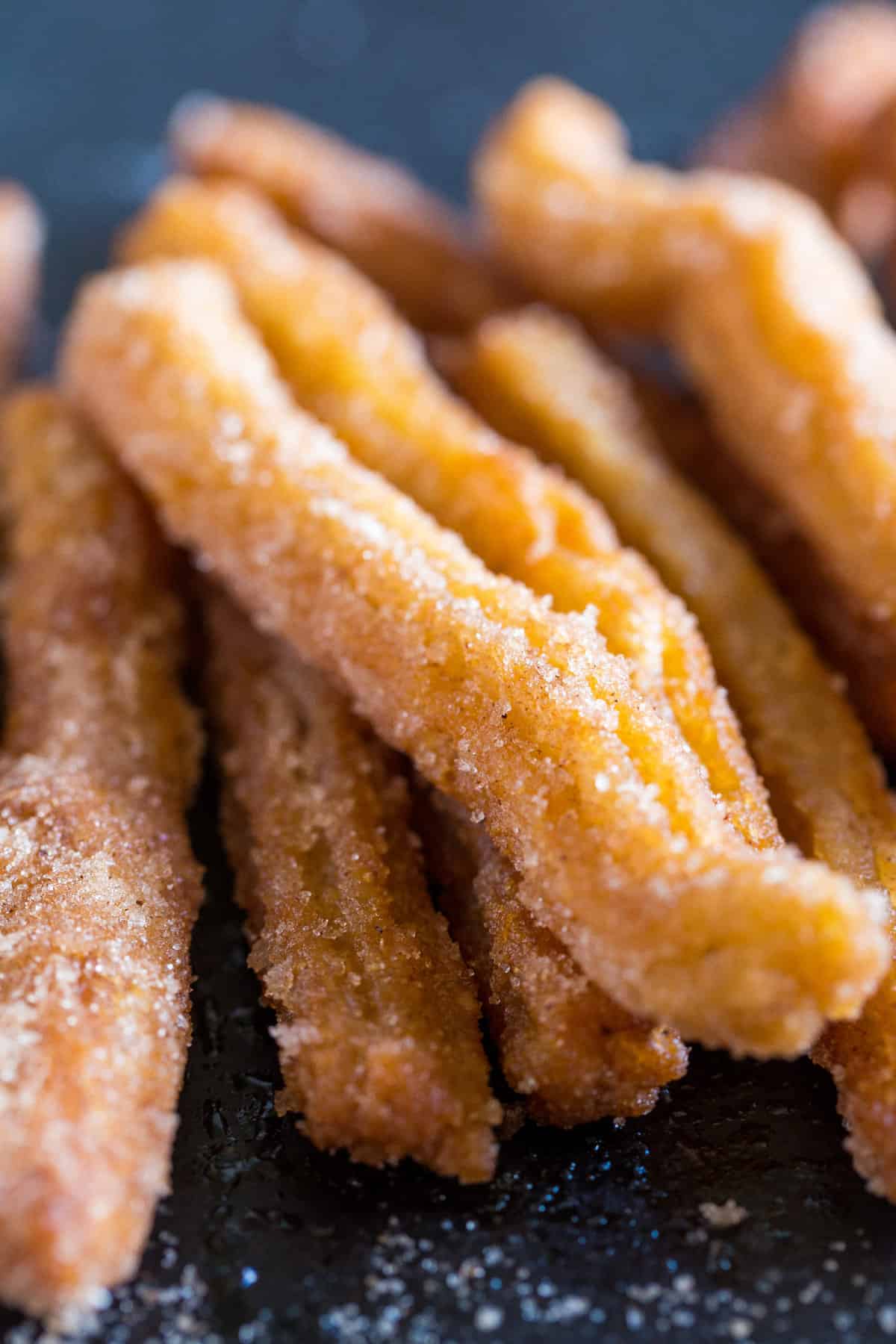 Mexican churros laid on a piece of black slate.