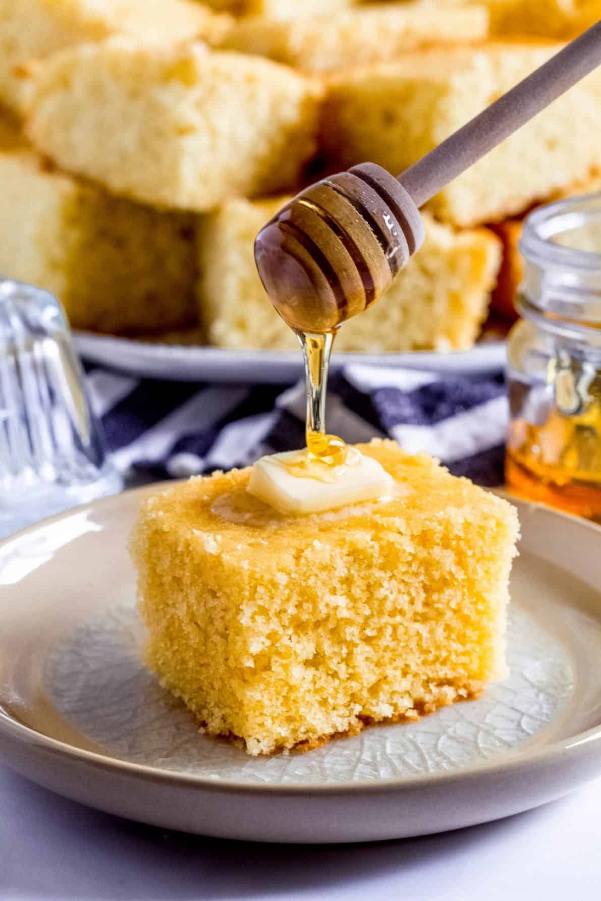 A piece of sweet buttermilk cornbread with a honey wand.
