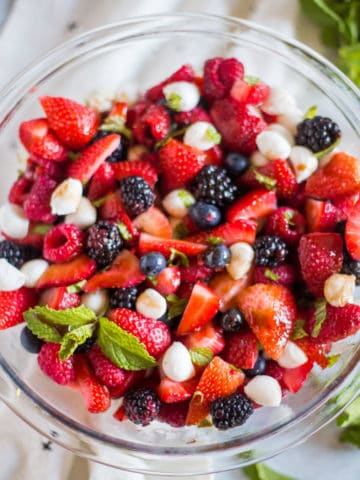 A glass bowl with berry caprese salad.