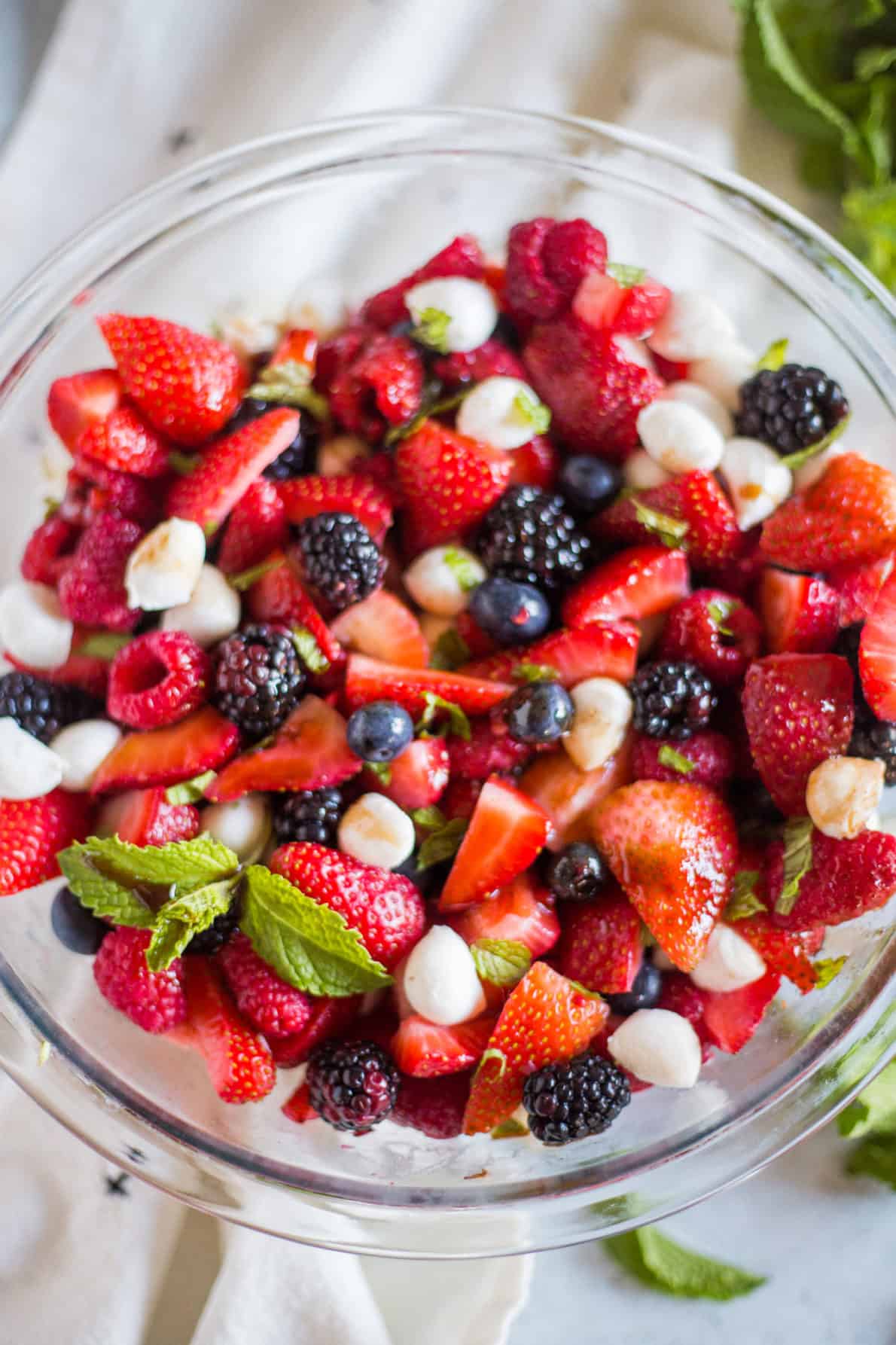 A glass bowl with berry caprese salad.