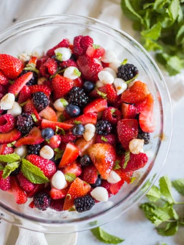 A glass bowl with berry caprese salad.