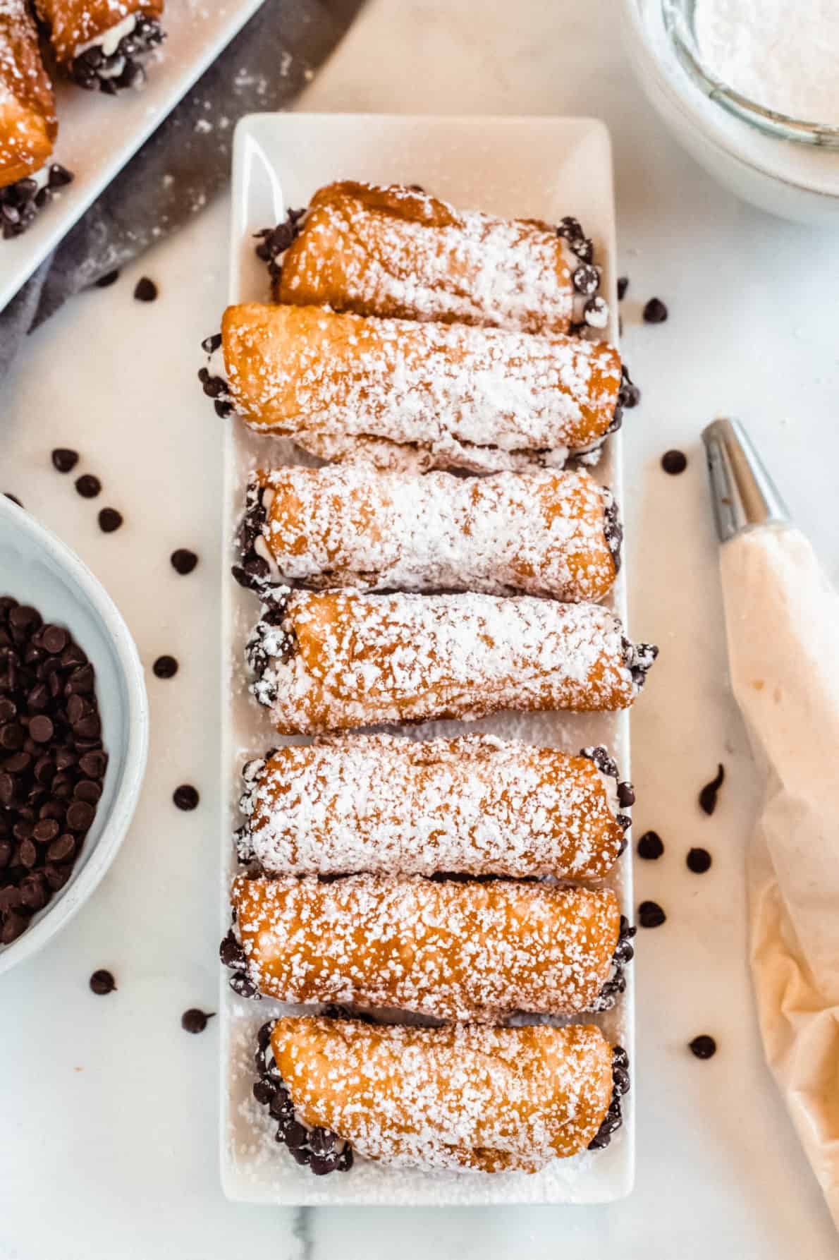 A line of homemade cannoli on a white plate.