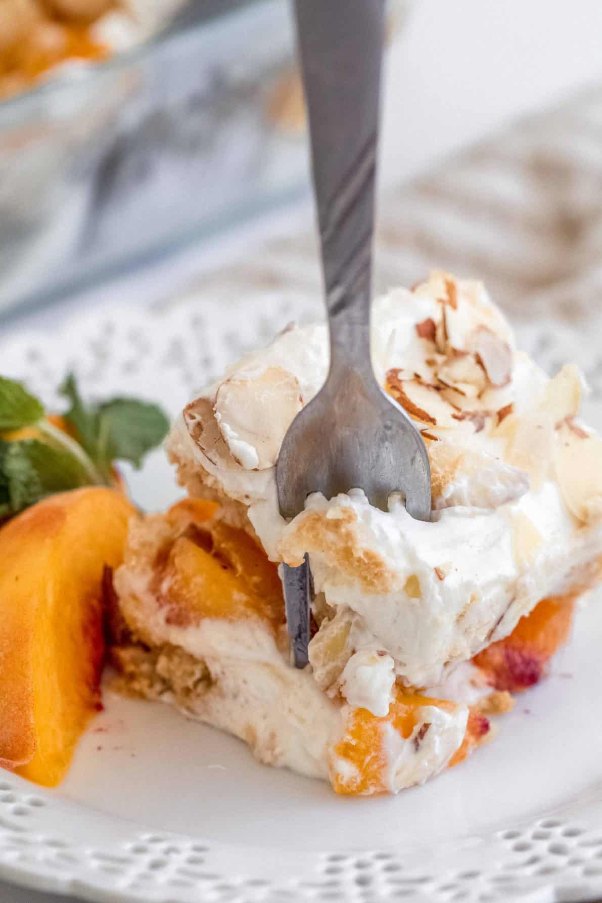 A piece of easy peach tiramisu with a fork in it.