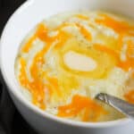 Cheesy grits topped with butter and cheese in a white bowl.