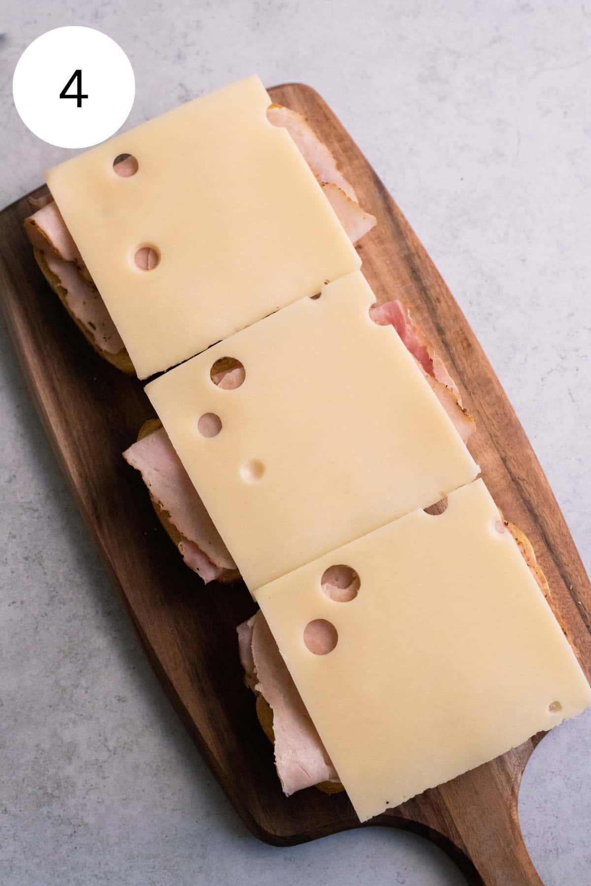 Four slices of cheese on a cutting board.