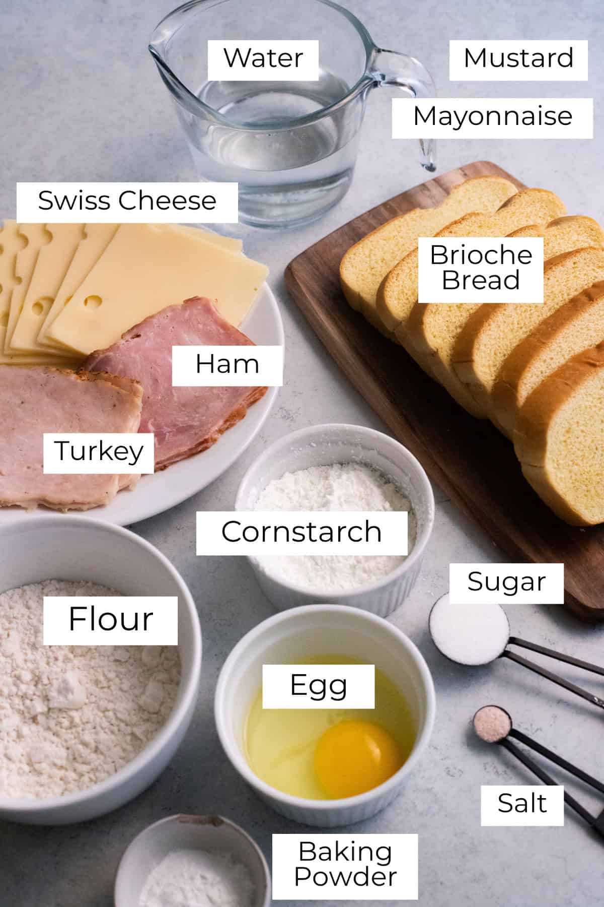 Labeled ingredients for monte cristo sandwich laid out on a gray surface.