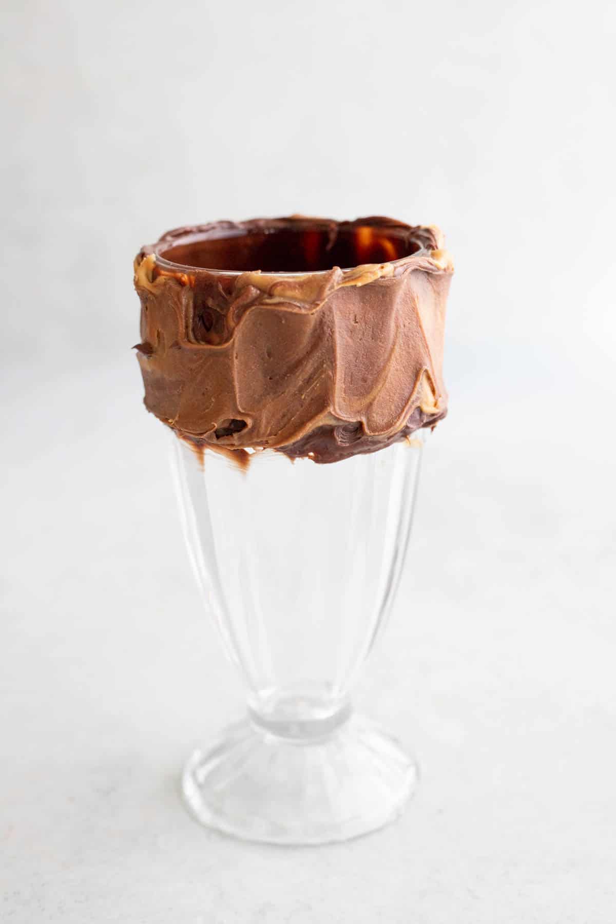 A milkshake glass with a frosted peanut butter rim.