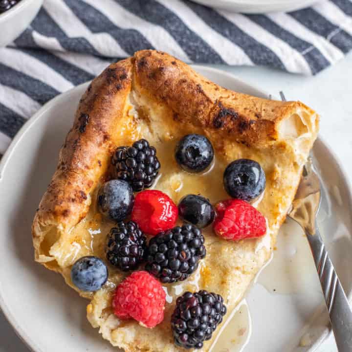 A white plate with a piece of a German pancake.