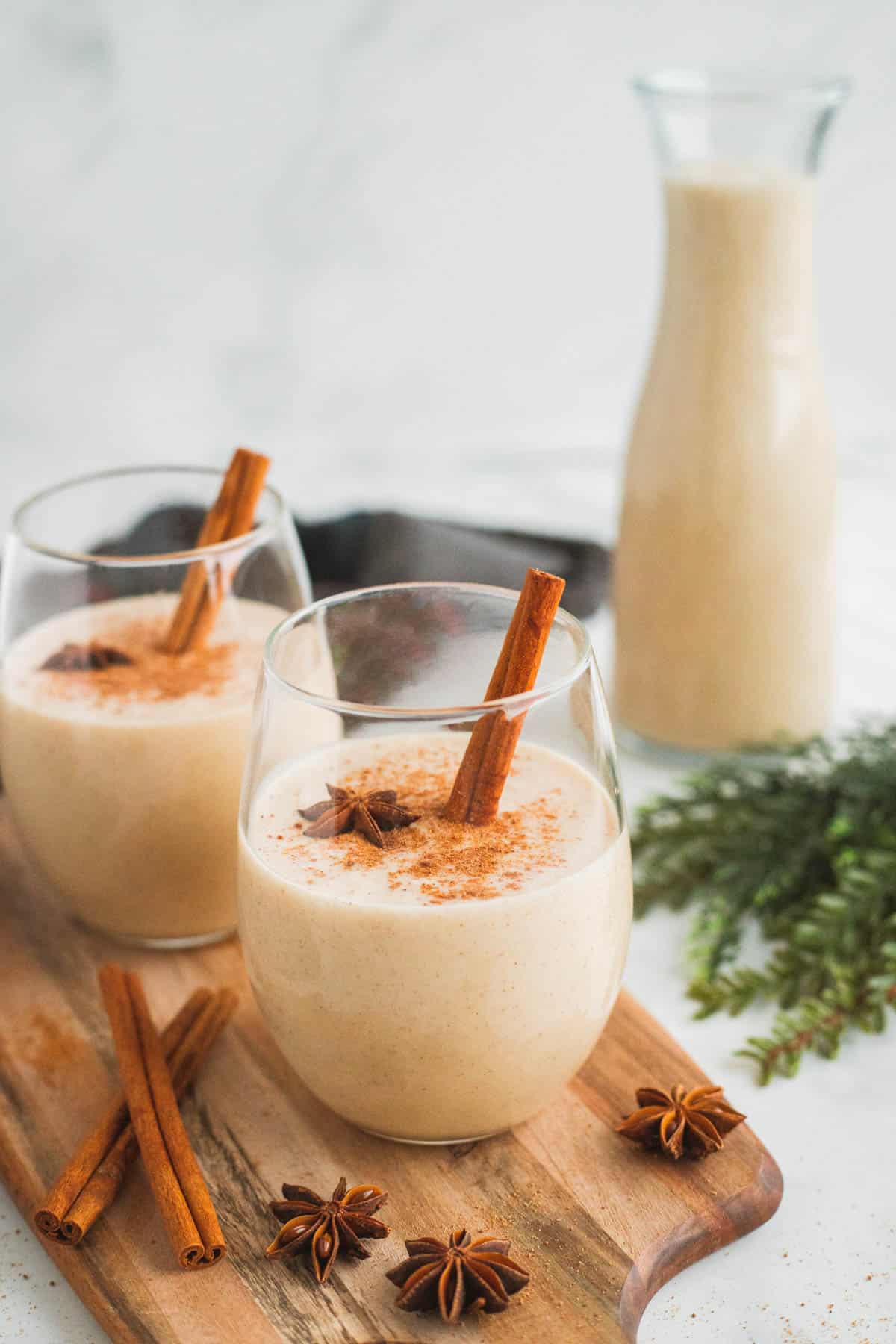 Two glasses of coquito on a wood surface.
