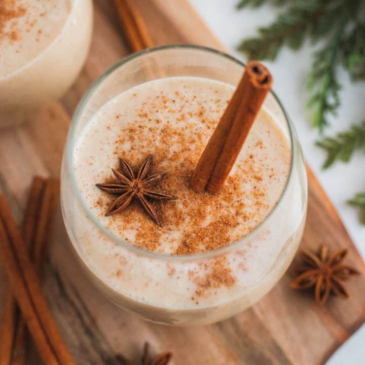 Coquito in a glass on a wooden surface.