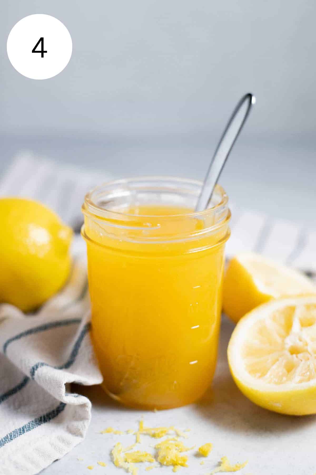 Lemon curd in a glass jar with a spoon.