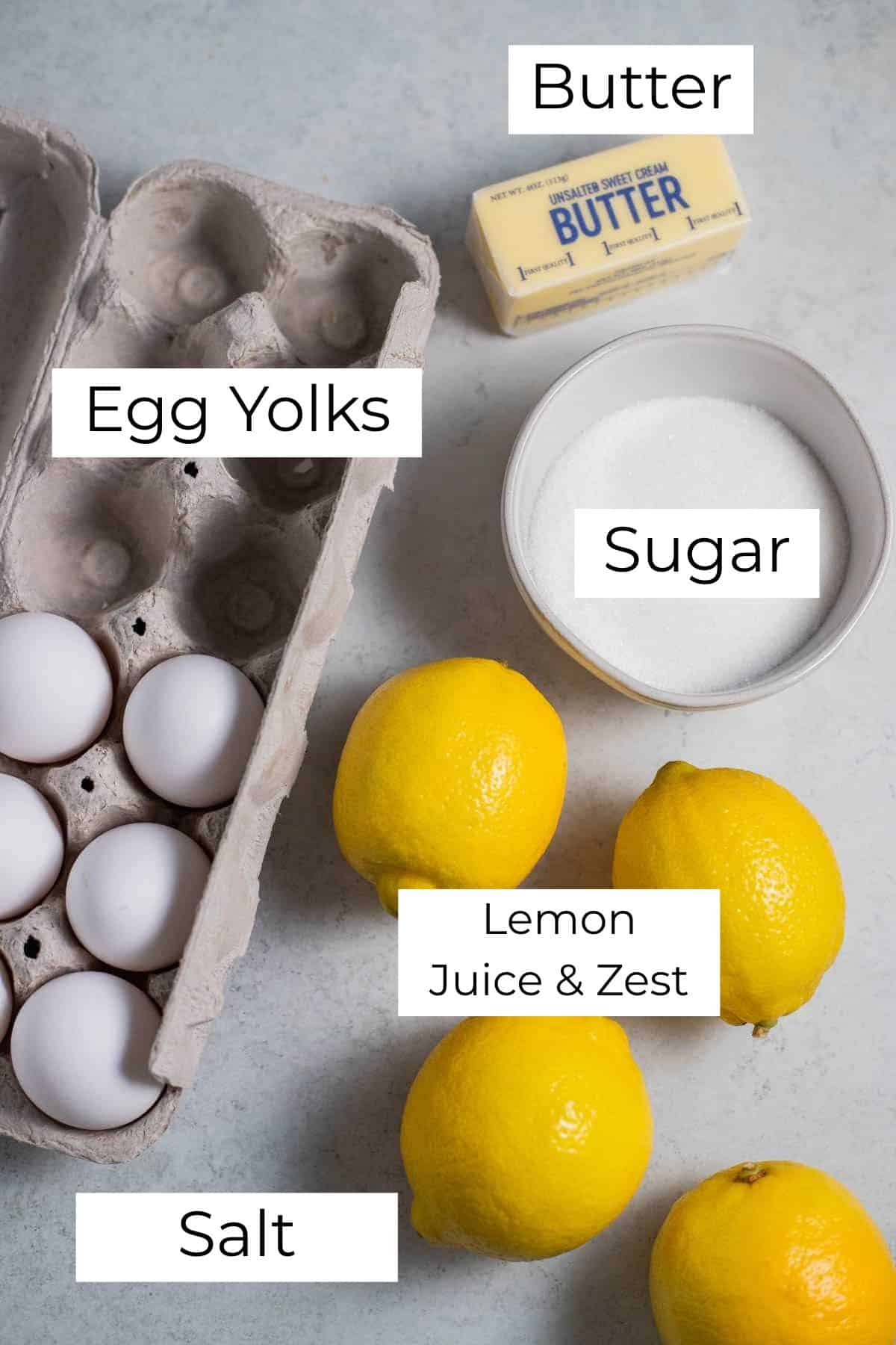 Labeled ingredients for lemon curd on a gray surface.