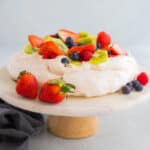 A classic pavlova on a white cake stand.