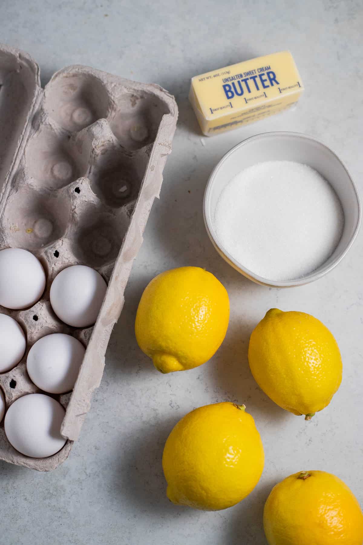 Ingredients for lemon curd on a gray surface.
