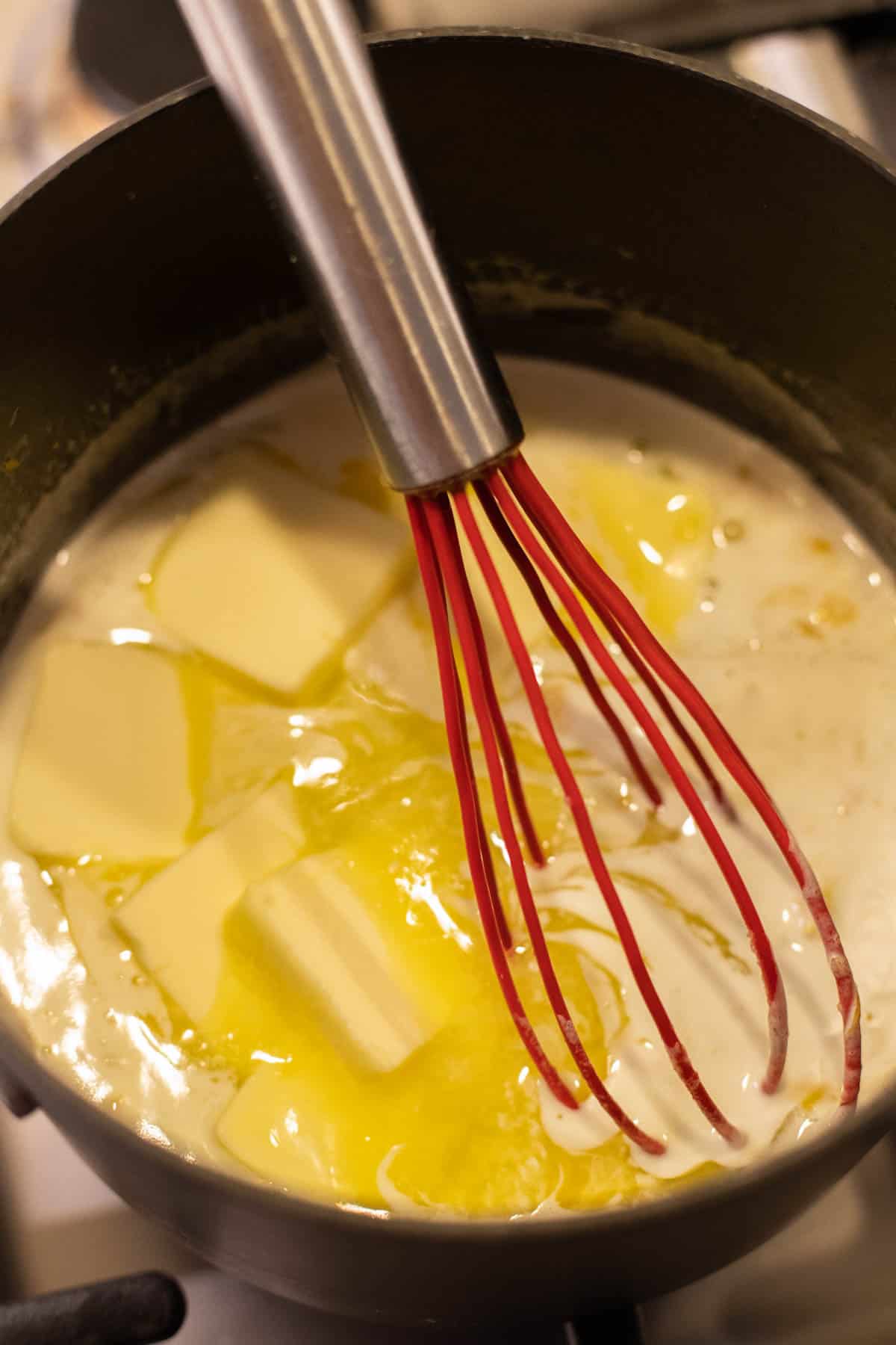 Ingredients for lemon curd in a saucepan with a whisk.