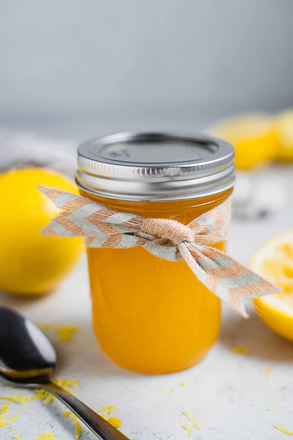 Lemon curd in a glass jar with a bow tied around it.