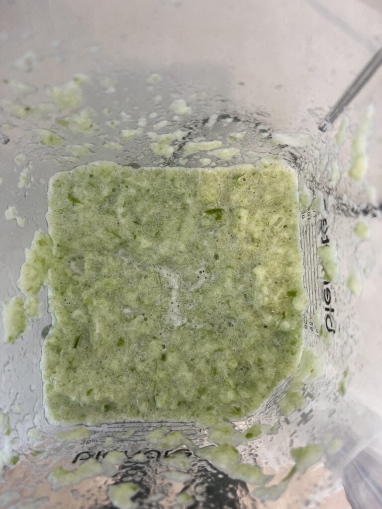 Top down view of a blender with wonton filling ingredients.