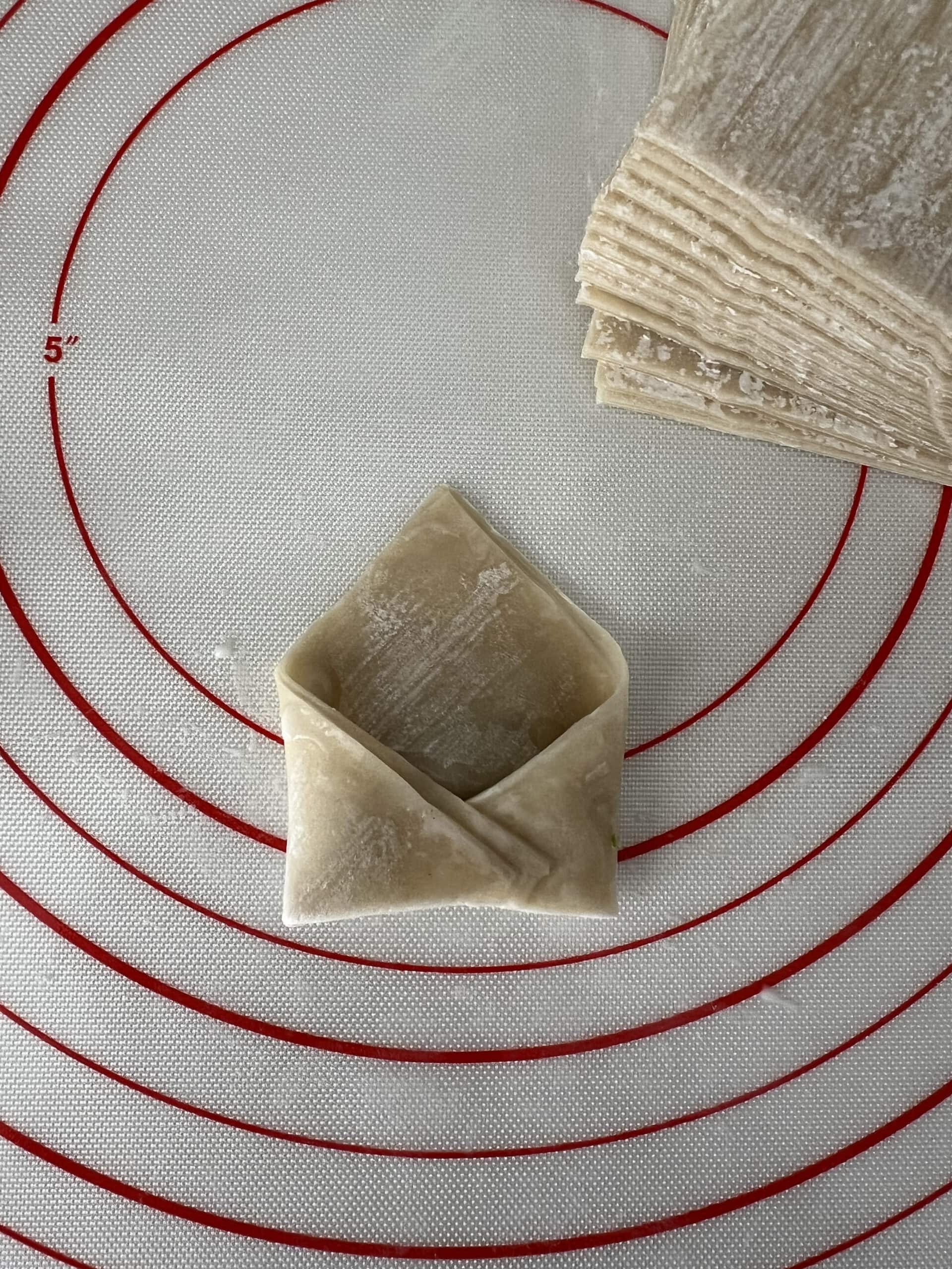 A wonton wrapper folded and ready to be fried.