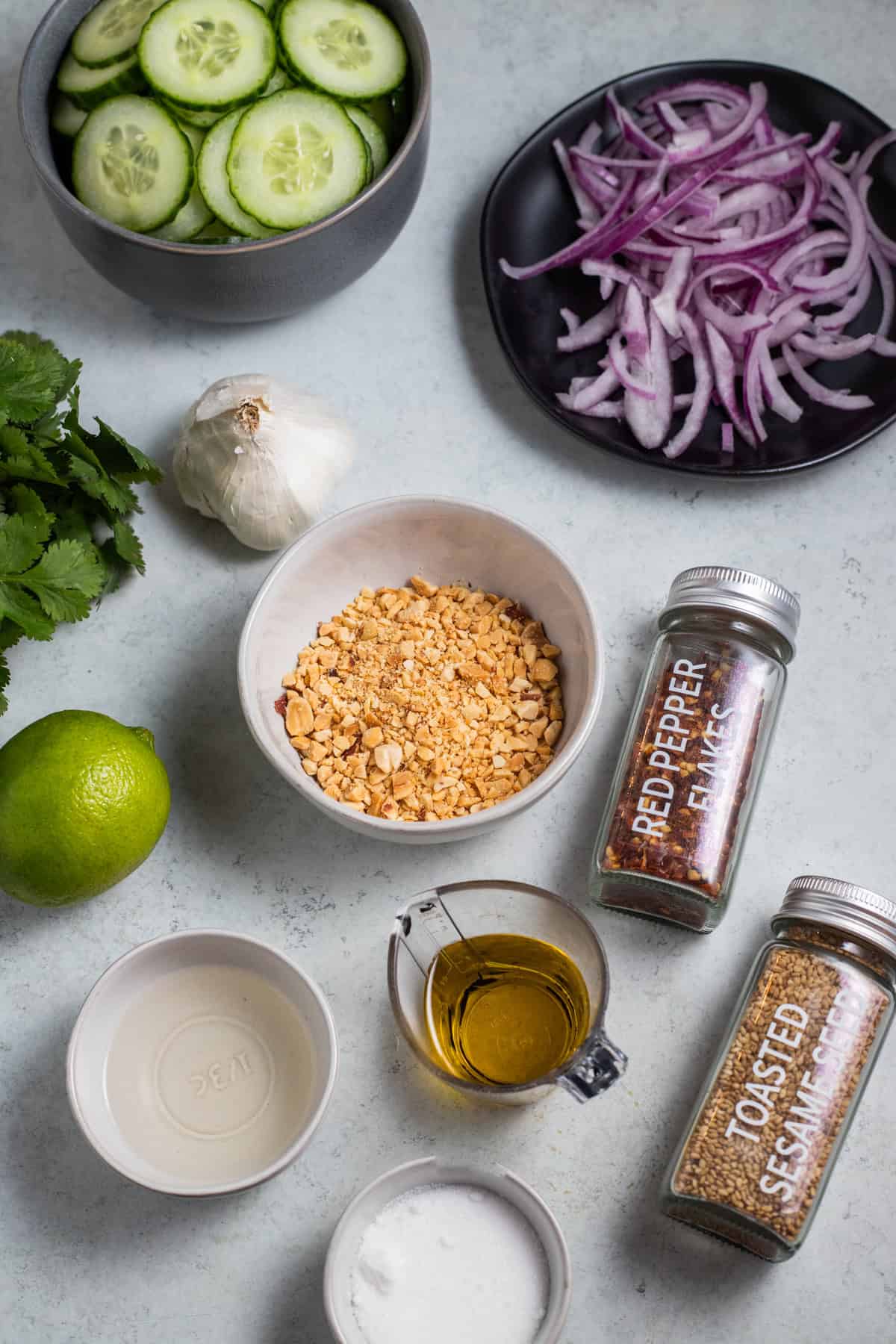 Ingredients laid out for thai cucumber salad on a gray surface.