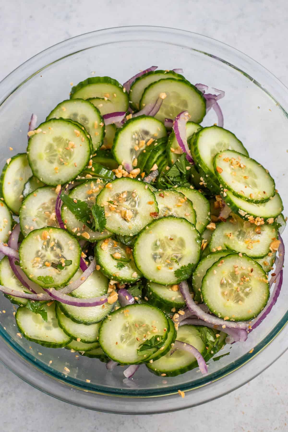 Thai Cucumber Salad mixed together in a glass mixing bowl.