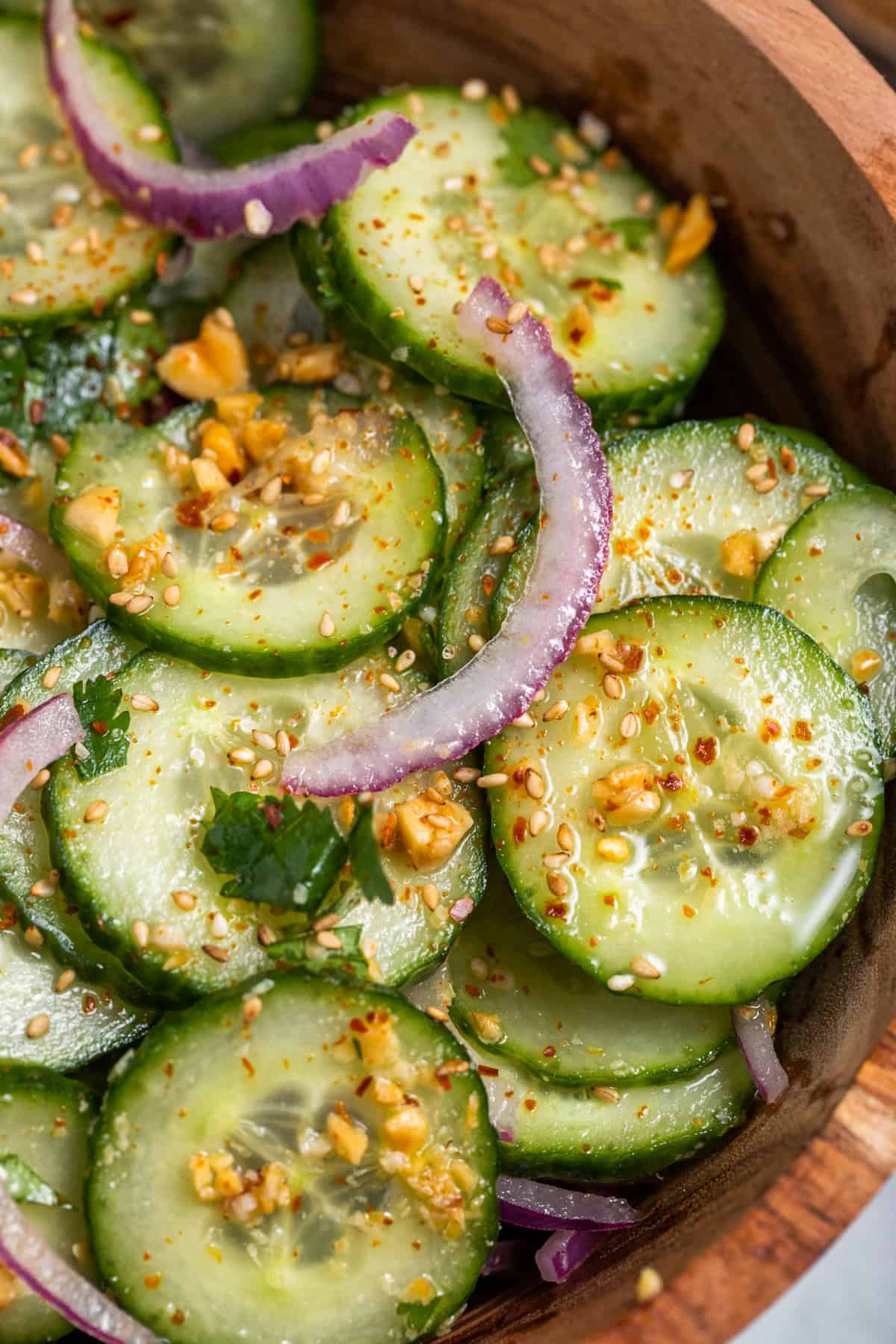 A close up photo of thai cucumber salad in a wood salad bowl.